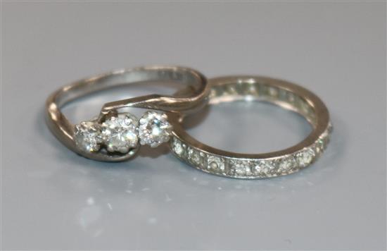 An 18ct gold ,platinum and three stone diamond crossover ring and a white metal and diamond full eternity ring.